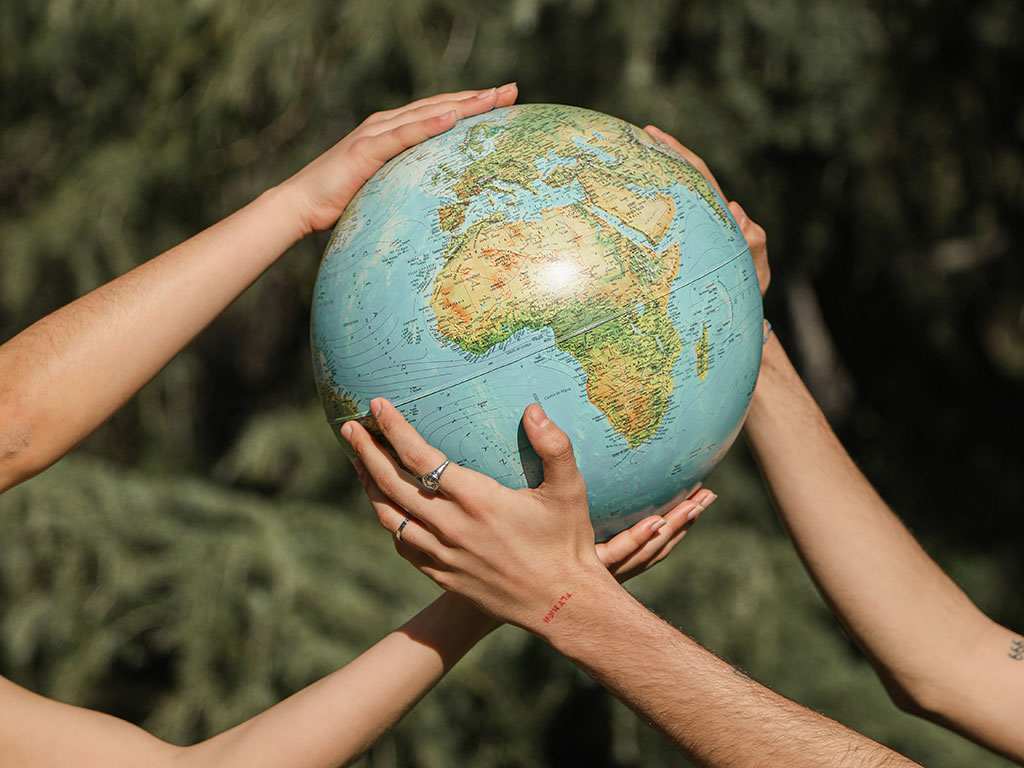 Two people holding a globe in their hands in front of a green forest