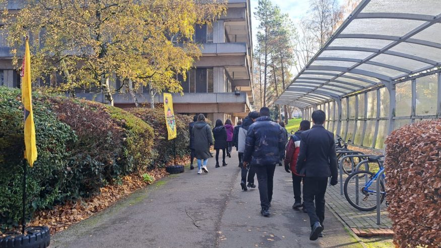 Group of students walking along pathway outside university.