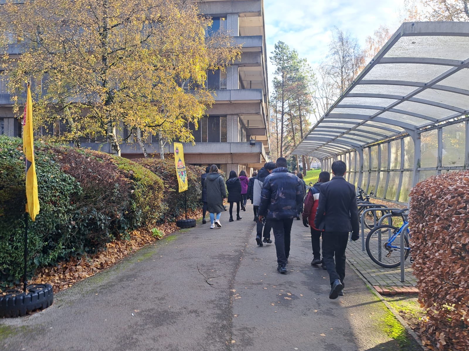 Group of students walking along pathway outside university. 