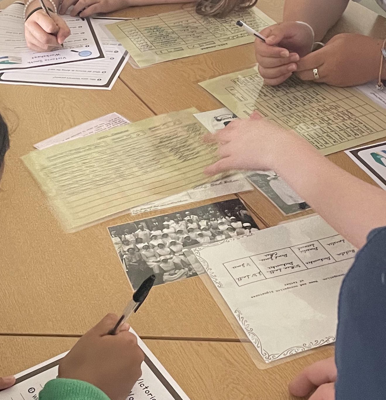 Hands look through materials including census', a photograph of nurses from WW1 and a marriage certificate