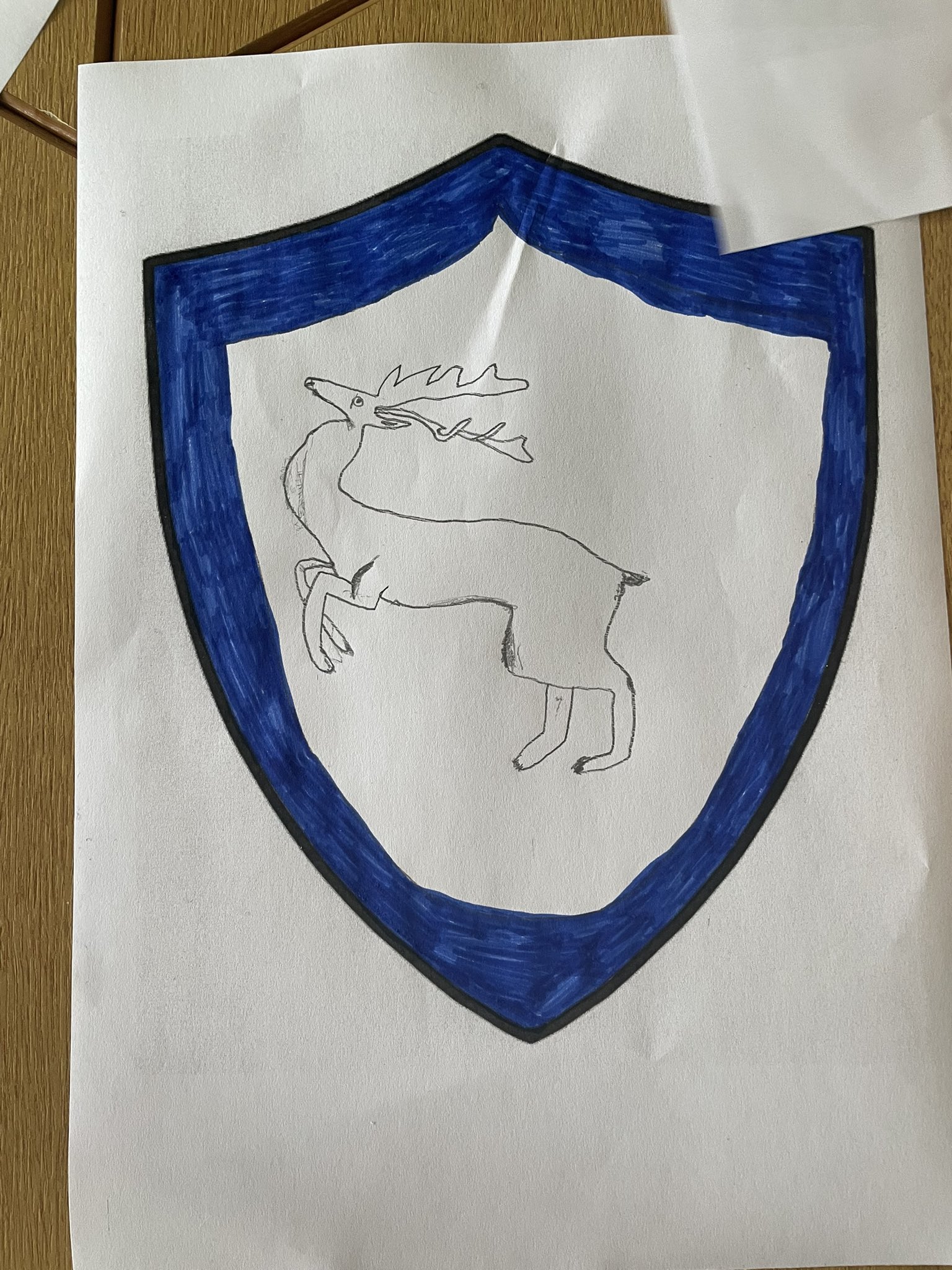 A shield with a blue outer edge and a rampant stag in the centre